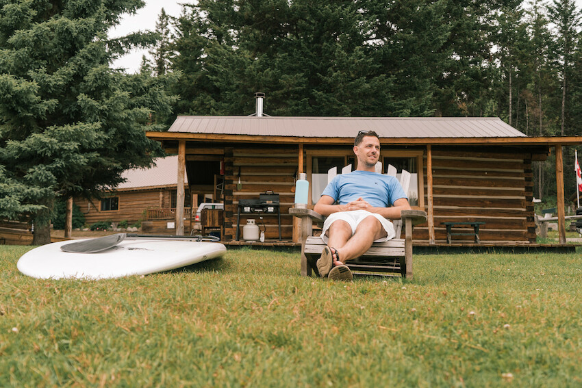 Man sitting in front of a cabin.
